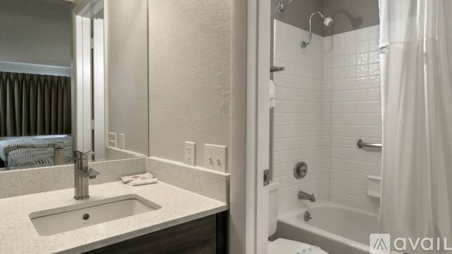A bathroom with a sink, mirror, and bathtub.