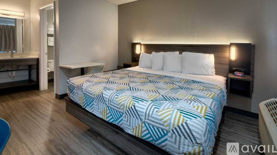 A bedroom with a bed covered in a blue and yellow patterned bedspread.