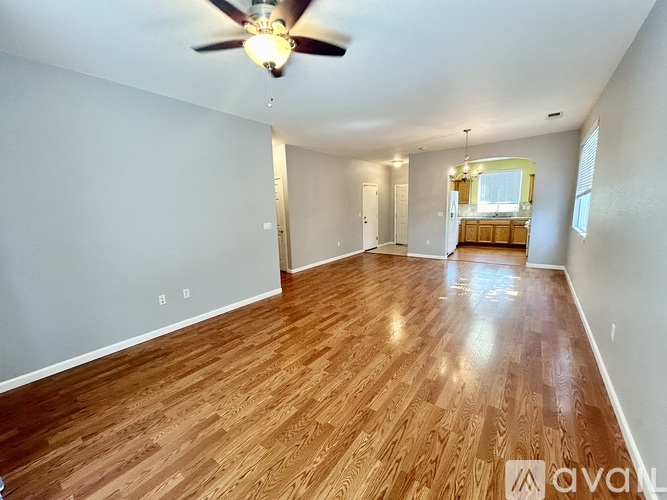A spacious room with wooden flooring and a ceiling fan.