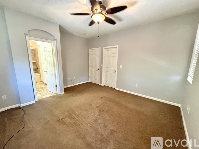 A room with a ceiling fan and carpeted floor.
