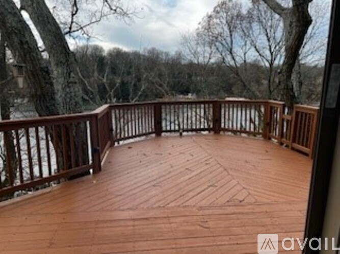 A wooden deck with a railing and a view of trees.