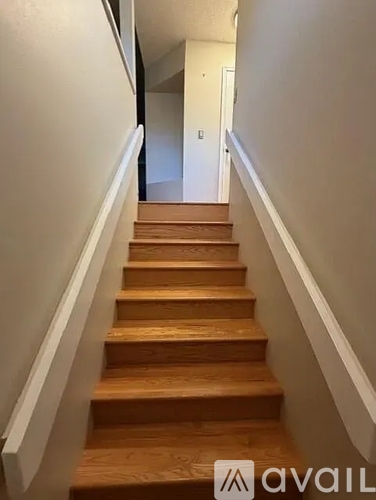 A set of wooden stairs with a white railing.