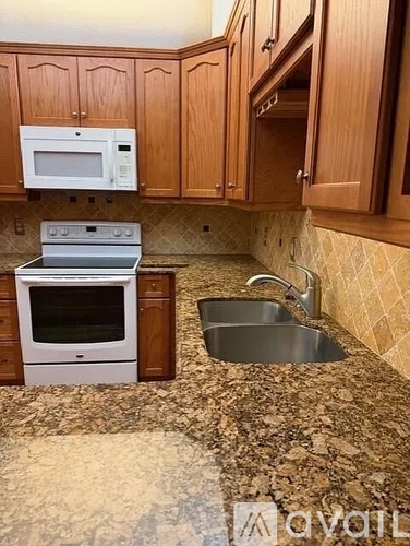 A kitchen with a stove, sink, and cabinets.