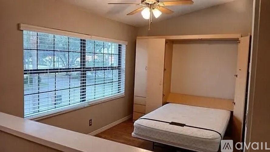 A bedroom with a bed, a window with blinds, and a ceiling fan.