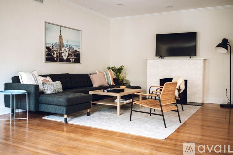 A living room with a green couch, a coffee table, a chair, a fireplace, and a painting on the wall.