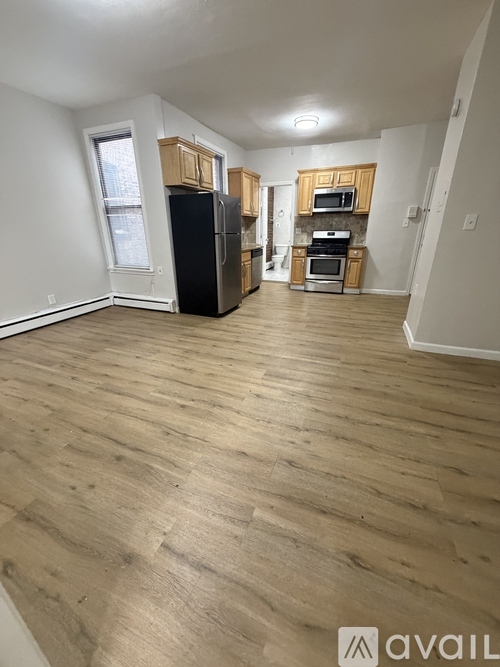 A kitchen with wooden floors and a black fridge.
