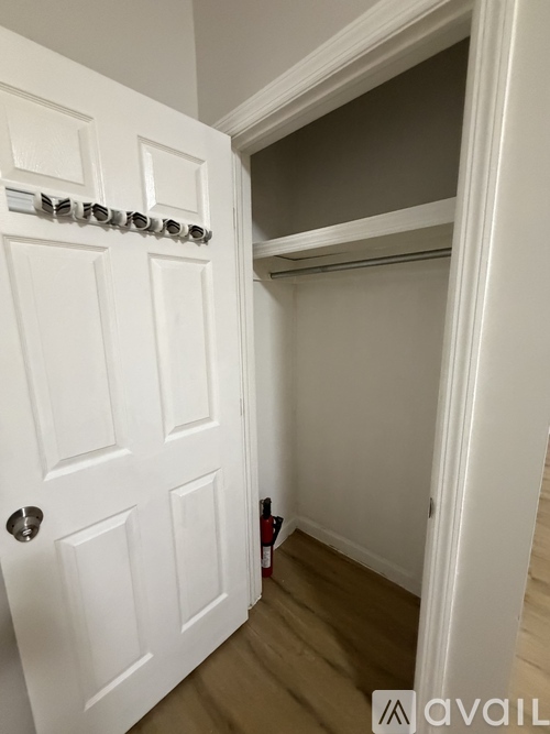A white door with a silver handle is open to a hallway.