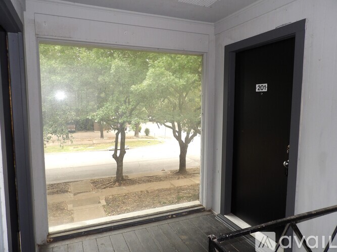 A view of a tree through a window with a door numbered 201.