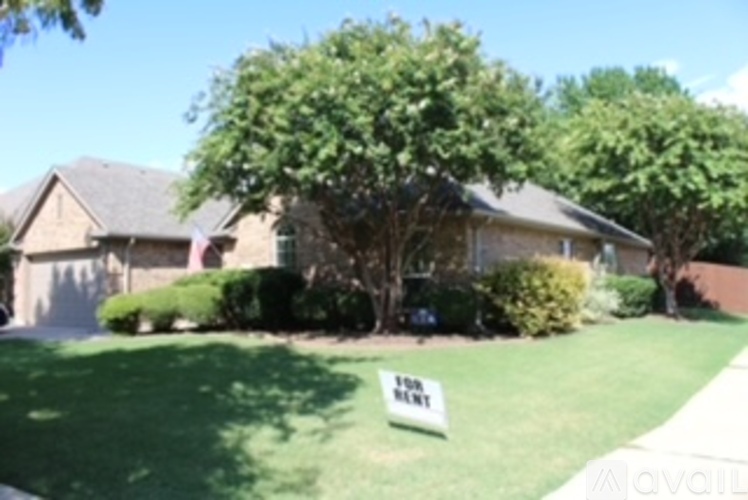 A house with a yard has a sign that says "For Rent".