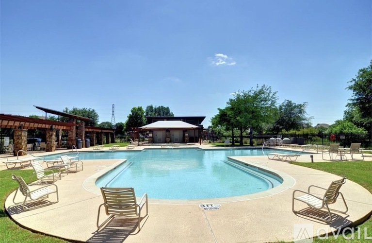 A pool with chairs around it and a gazebo in the background.