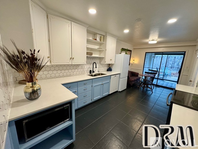 A kitchen with white cabinets and a black countertop.