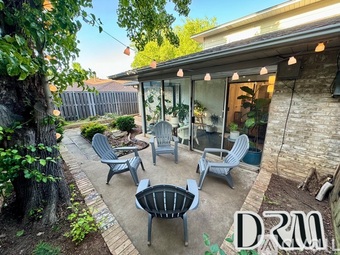A patio with a table and chairs is surrounded by a fence and trees.