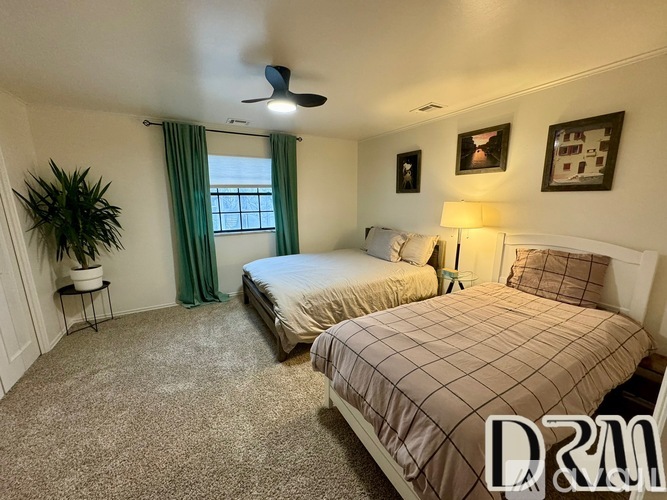A bedroom with two beds and a ceiling fan.