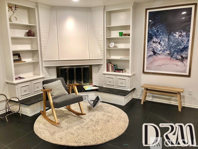 A living room with a chair, a bench, and a painting on the wall.