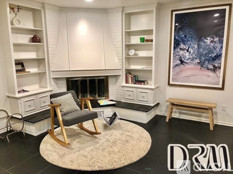 A living room with a chair, a bench, and a painting on the wall.