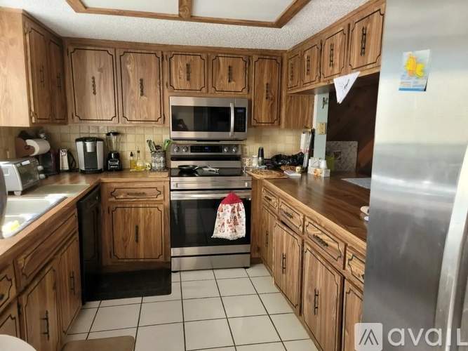 A kitchen with wooden cabinets and a stainless steel refrigerator.
