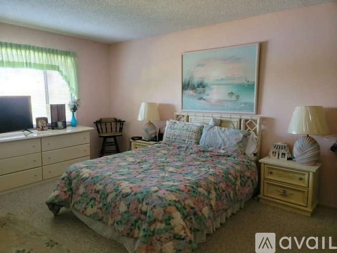 A bedroom with a floral bedspread and a painting on the wall.