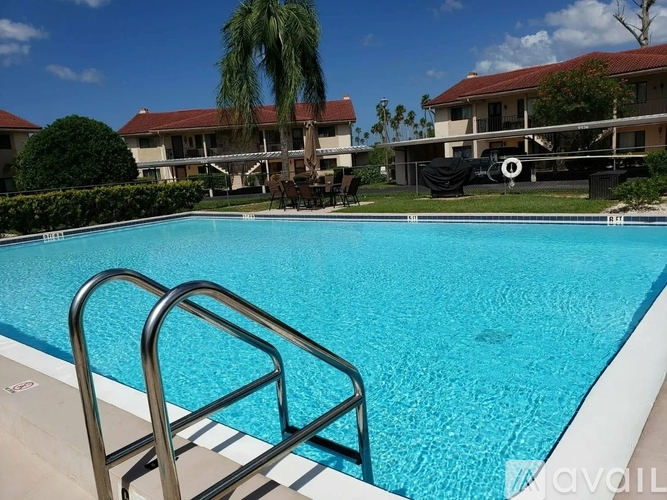 A swimming pool with a ladder in the foreground and a building in the background.