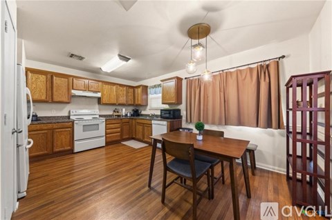 A kitchen with wooden floors and a table set for two.