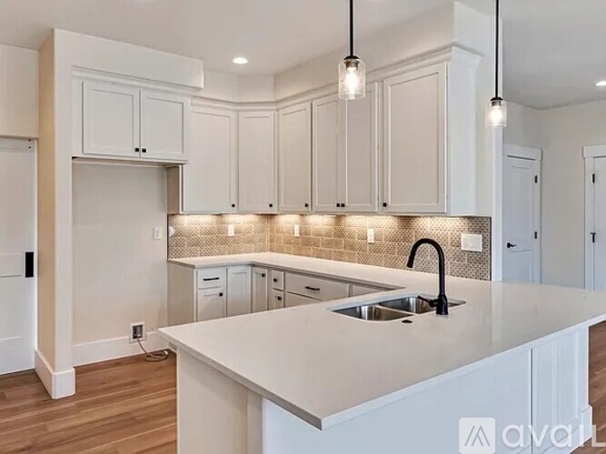 A kitchen with white cabinets and a countertop with a sink.