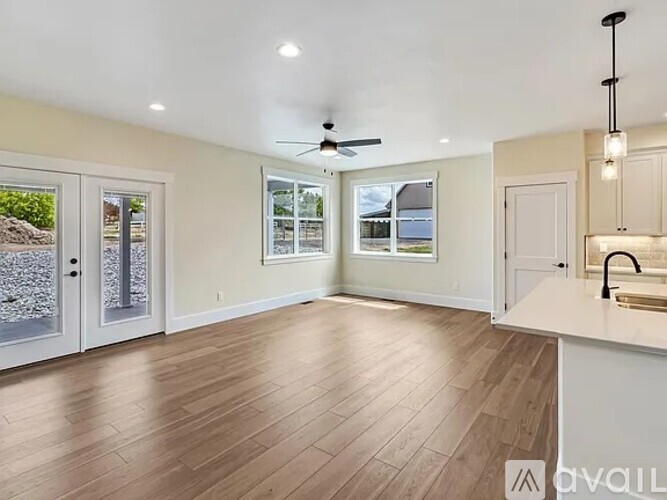 A spacious room with a kitchen area and a ceiling fan.