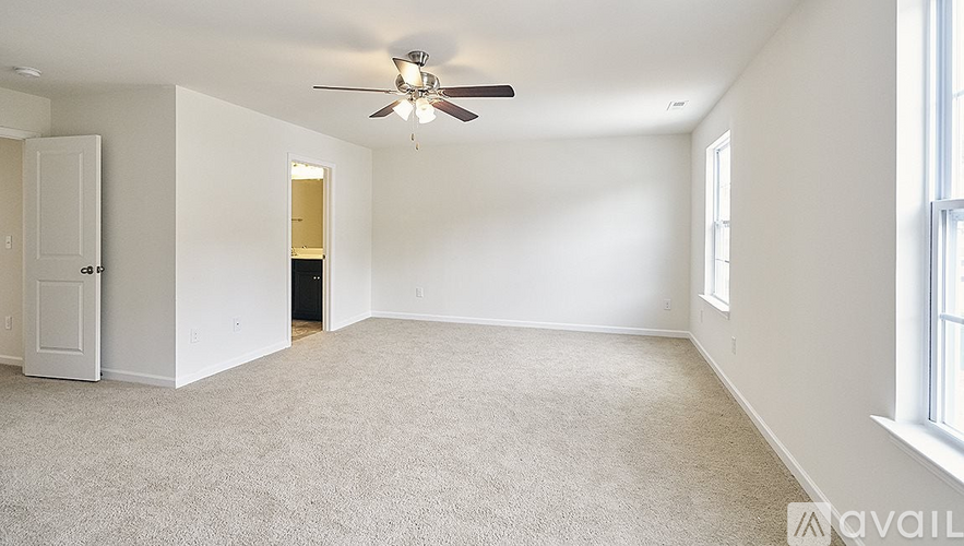 A spacious room with a ceiling fan and carpeted floor.