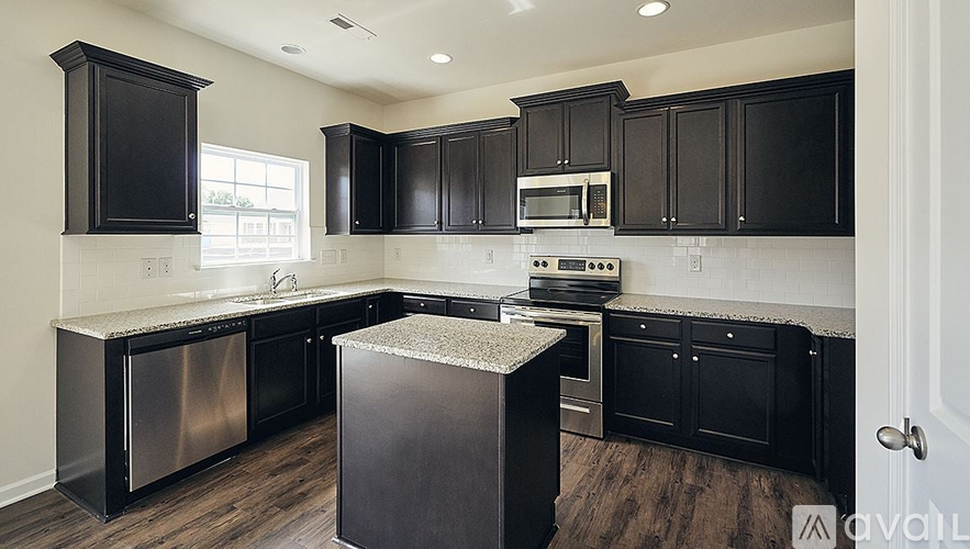 A kitchen with black cabinets and a stainless steel dishwasher.
