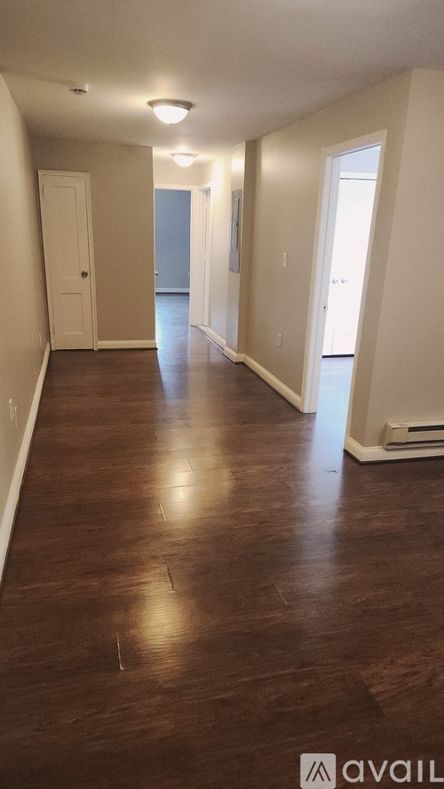 A long hallway with wood floors and white walls.