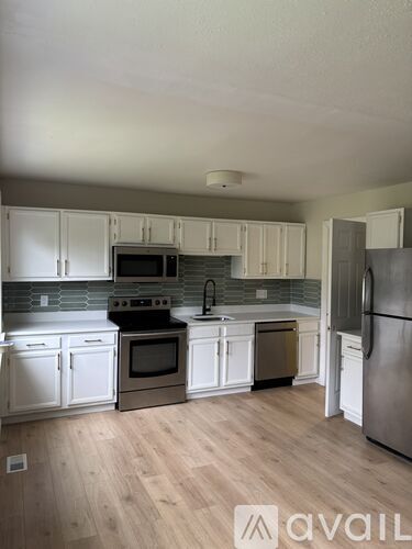 A kitchen with white cabinets and a wooden floor.