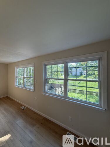 A room with two windows and wooden flooring.