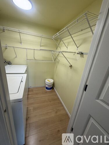 A laundry room with a washer and dryer and a bucket on the floor.
