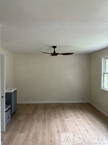 A room with a ceiling fan and wooden flooring.
