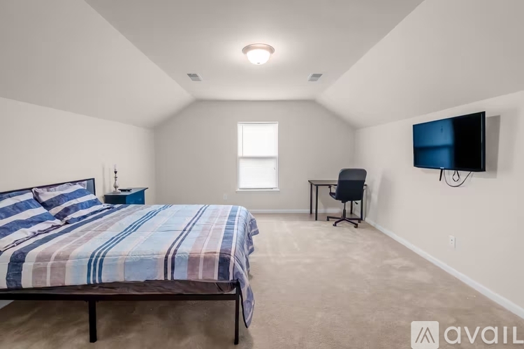 A bedroom with a bed, desk, and chair.