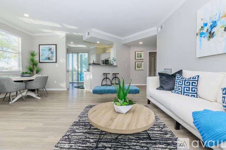 A living room with a white couch, a round wooden coffee table, and a rug with a plant on it.