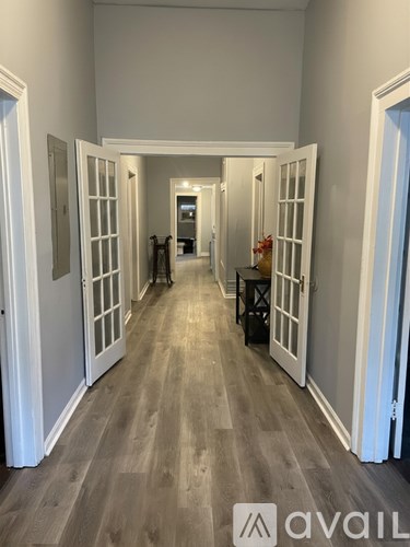 A hallway with white doors and a wooden floor.