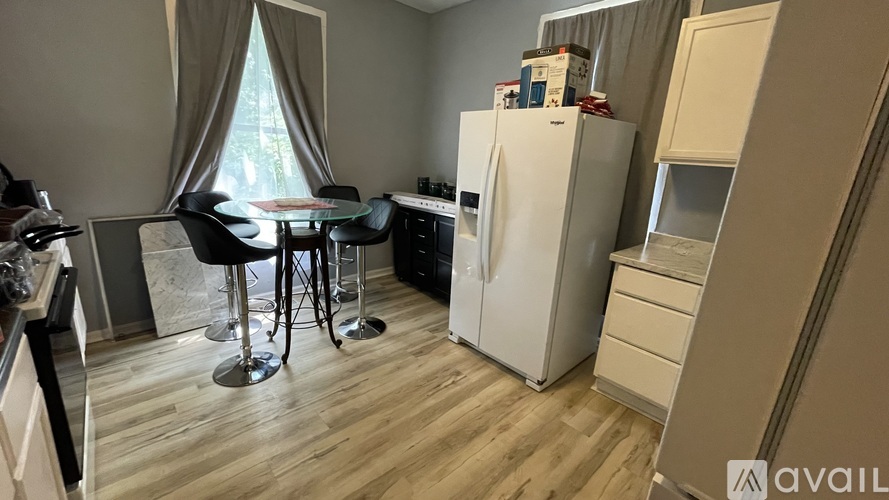 A kitchen with a white fridge, a dining table with chairs, and a cabinet.