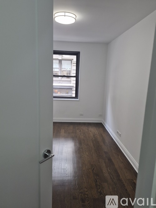 A room with a wooden floor and a door leading to a balcony.