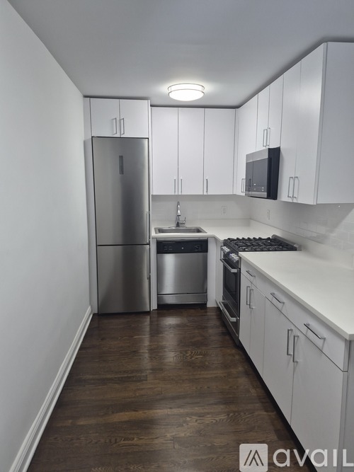 A kitchen with white cabinets and a stainless steel refrigerator.