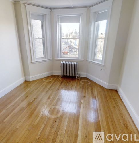 A room with wooden floors and a window overlooking a construction site.