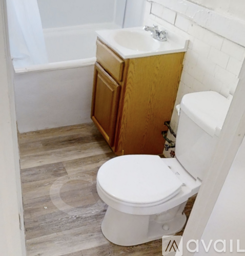 A white toilet in a bathroom with a wooden cabinet and a white sink.
