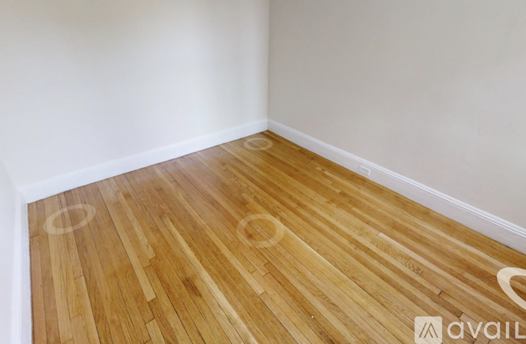 A room with wooden flooring and a white wall.