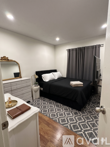 A bedroom with a black bed and a white dresser.