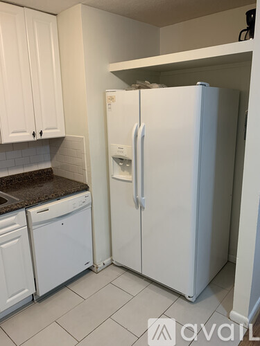 A white refrigerator is in a kitchen with white cabinets.