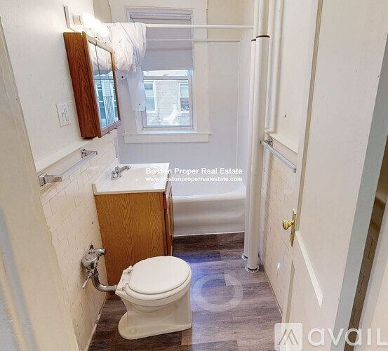 A bathroom with a toilet, sink, and a window.