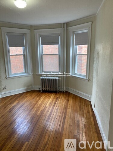 A room with wooden floors and three windows.