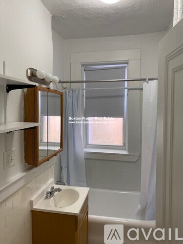 A bathroom with a sink, mirror, and a window with a curtain.