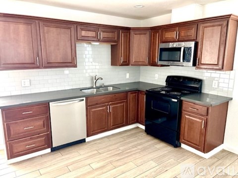 A kitchen with wooden cabinets and a black stove top oven.