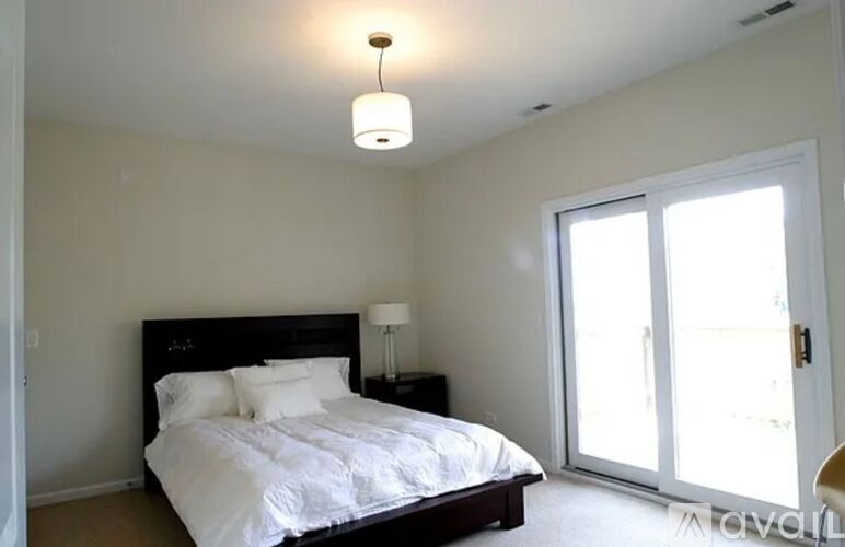 A bedroom with a bed, nightstand, and a window with a sliding door.