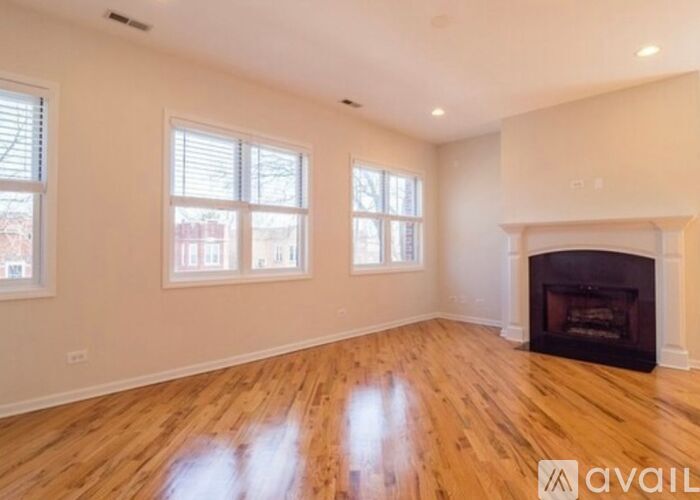 A spacious room with a fireplace and wooden flooring.