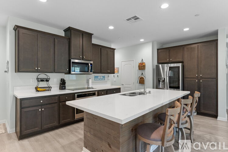 A modern kitchen with dark brown cabinets and a white island.